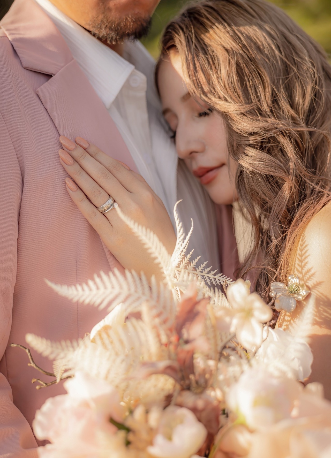 新婦が新郎の胸元に寄り添い、指輪とブーケが見える前撮りのクローズアップ写真