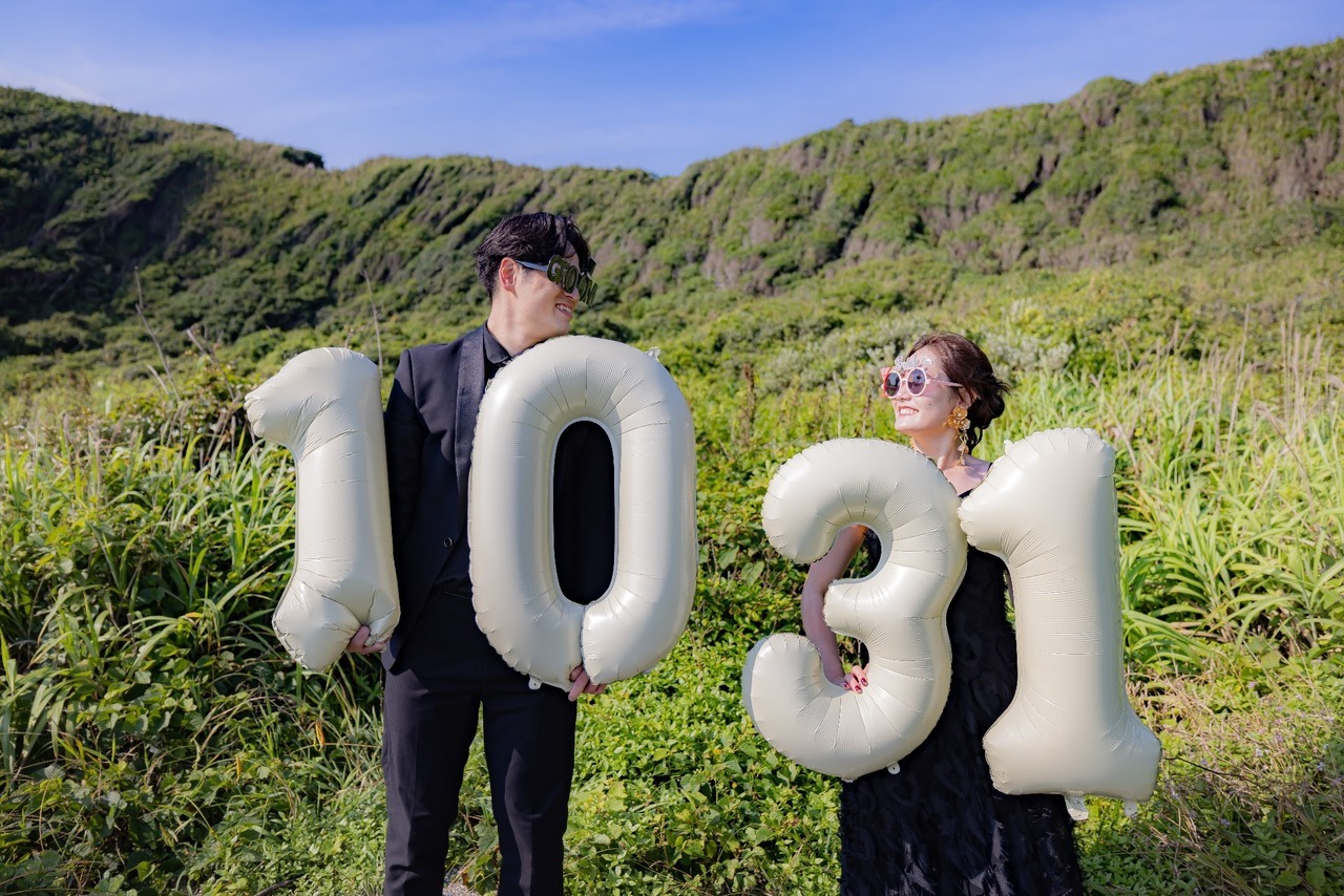 城ヶ島の緑を背景に10と31のバルーンを持つ新郎新婦の前撮り