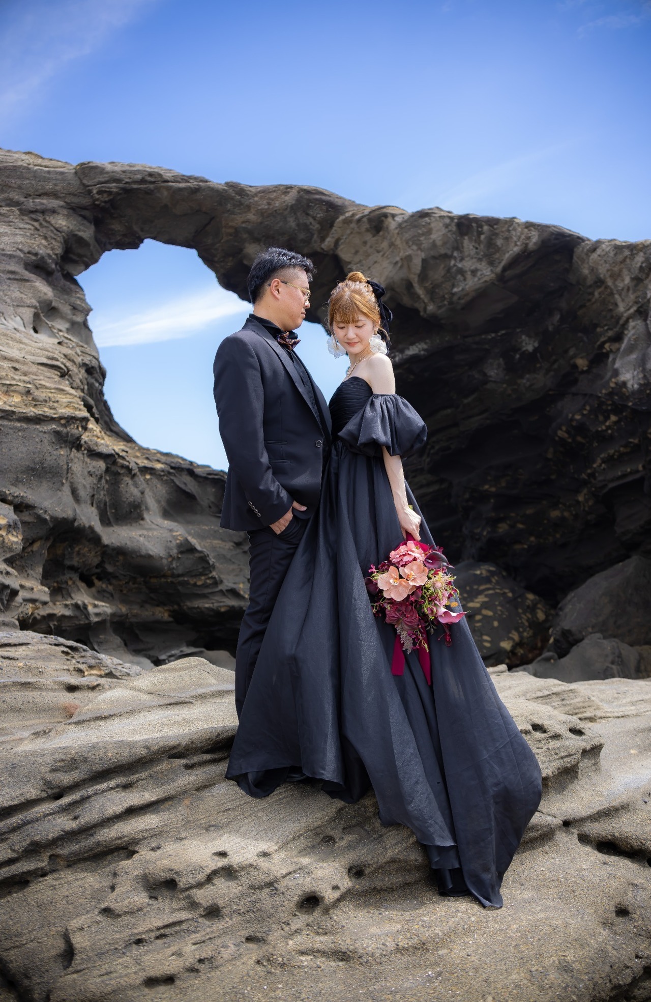 城ヶ島の岩場で黒いドレスとブラックスーツを着て寄り添う新郎新婦
