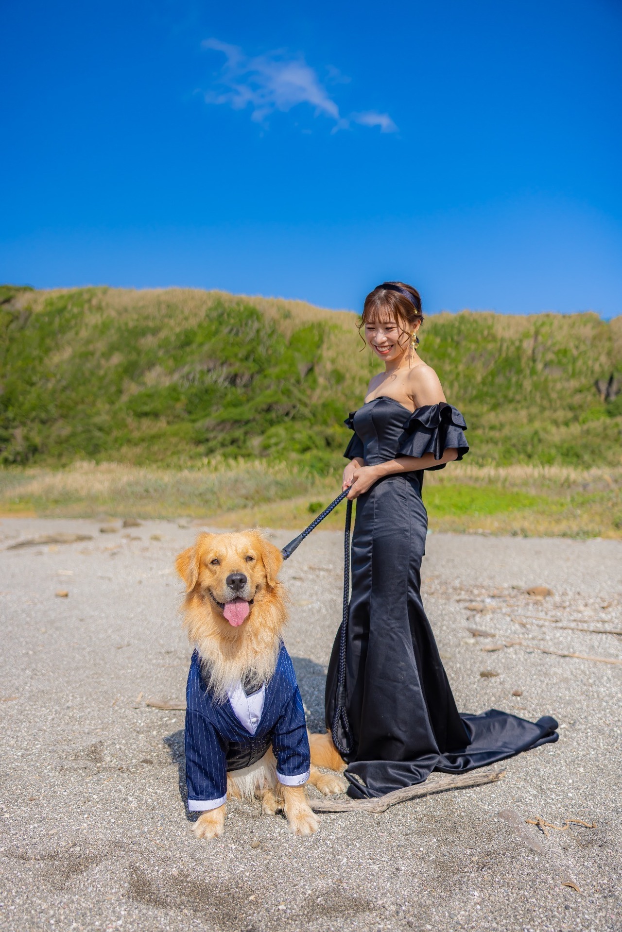 青空の城ヶ島で黒ドレス姿の新婦とネイビーのスーツを着たゴールデンレトリバー