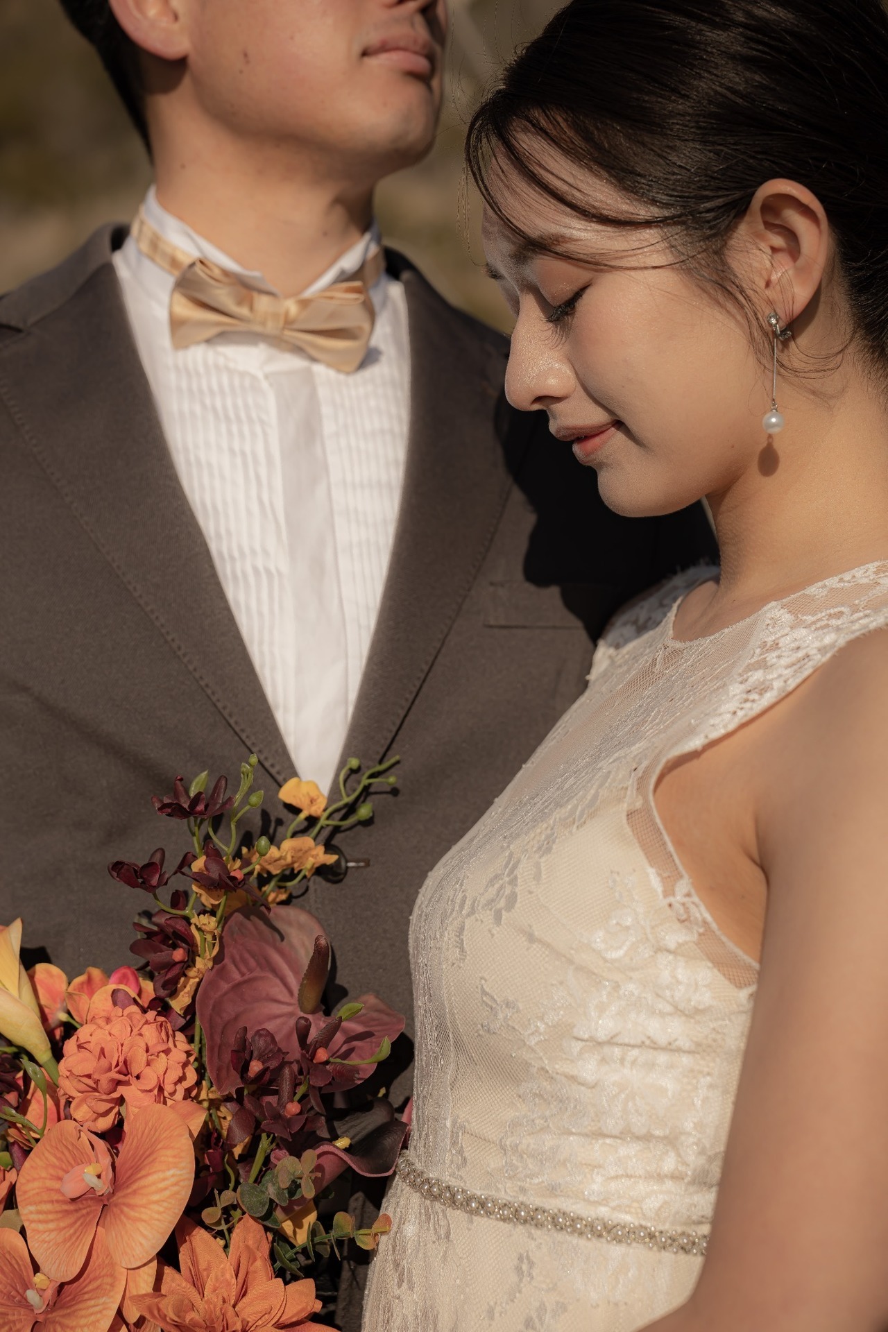 城ヶ島前撮りでオレンジ色のブーケを持つ新婦と寄り添う新郎のウェディングポートレート