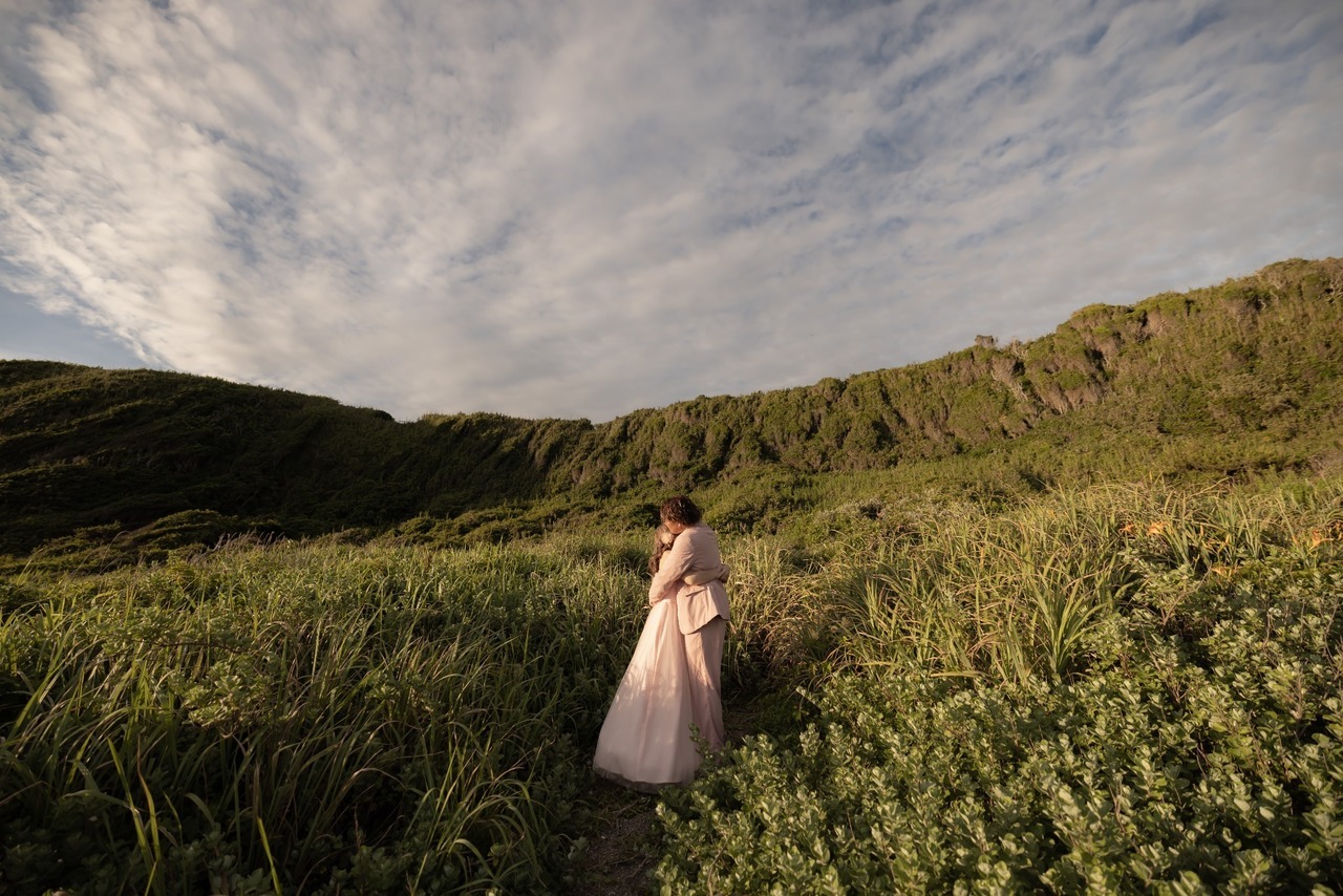 城ヶ島の草原エリアで抱き合う新郎新婦を遠景で写した前撮り写真