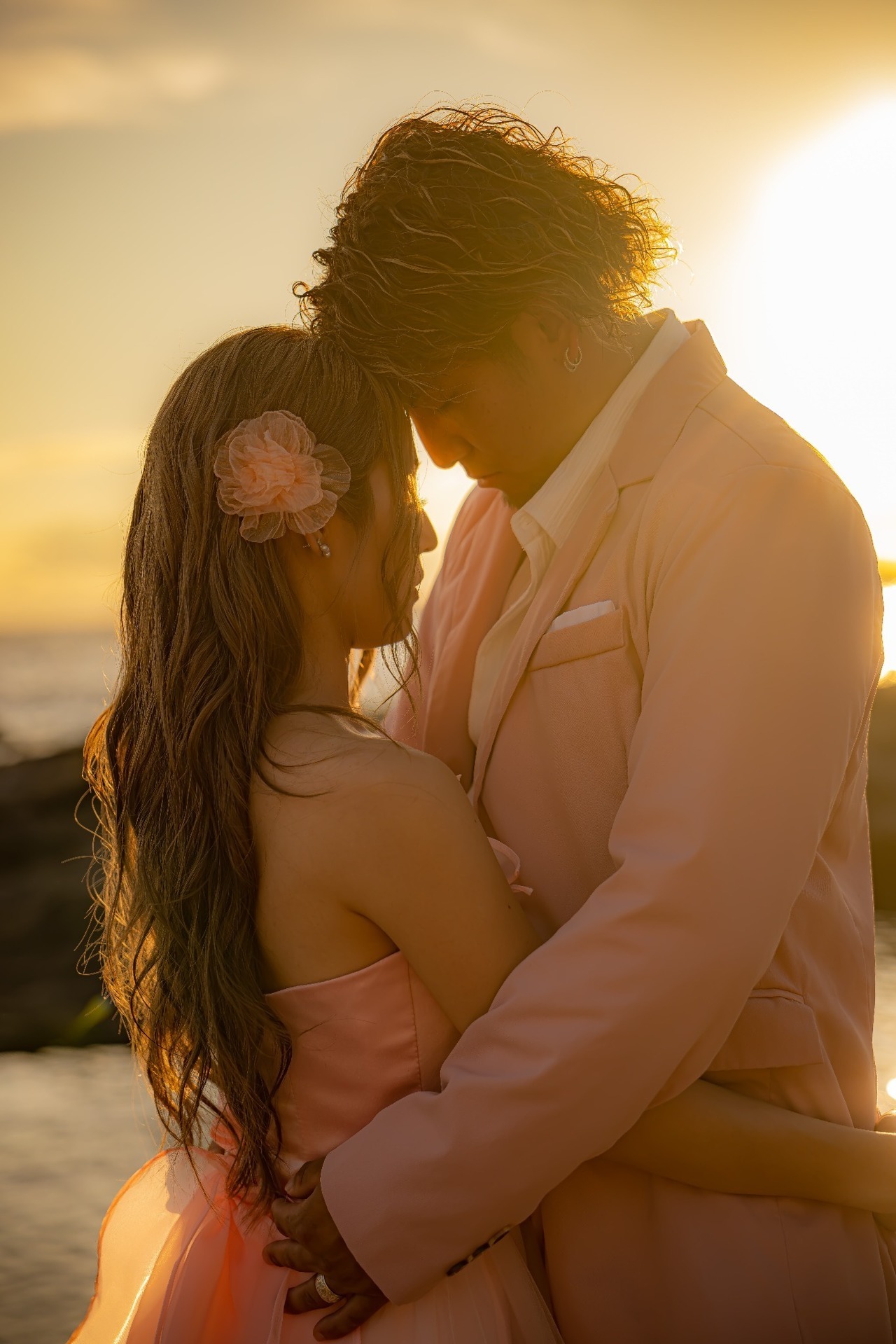 夕陽を逆光にして抱き合う新郎新婦を近距離で撮影した前撮り写真