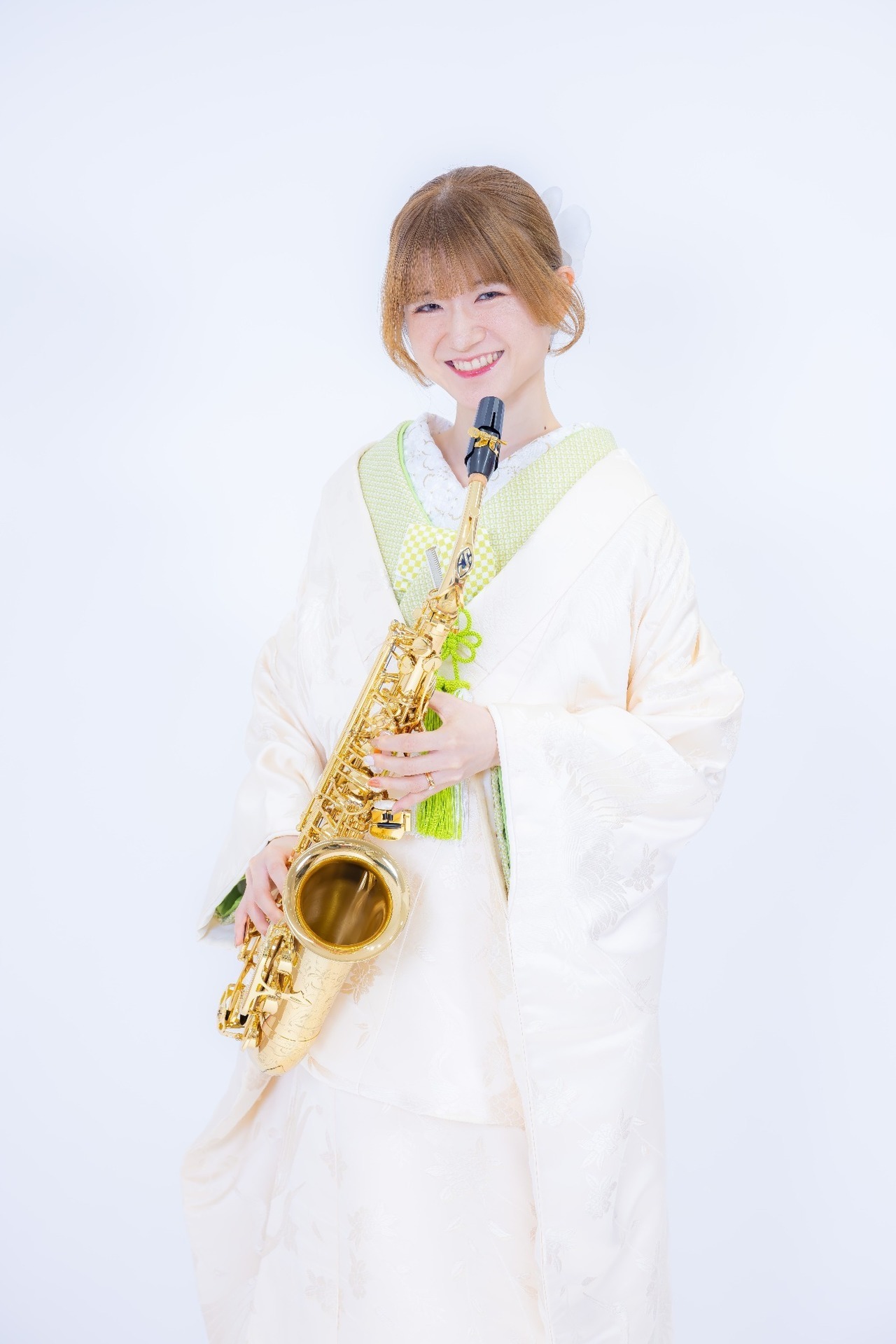 白を基調とした和装姿でサックスを持ち笑顔を見せる新婦