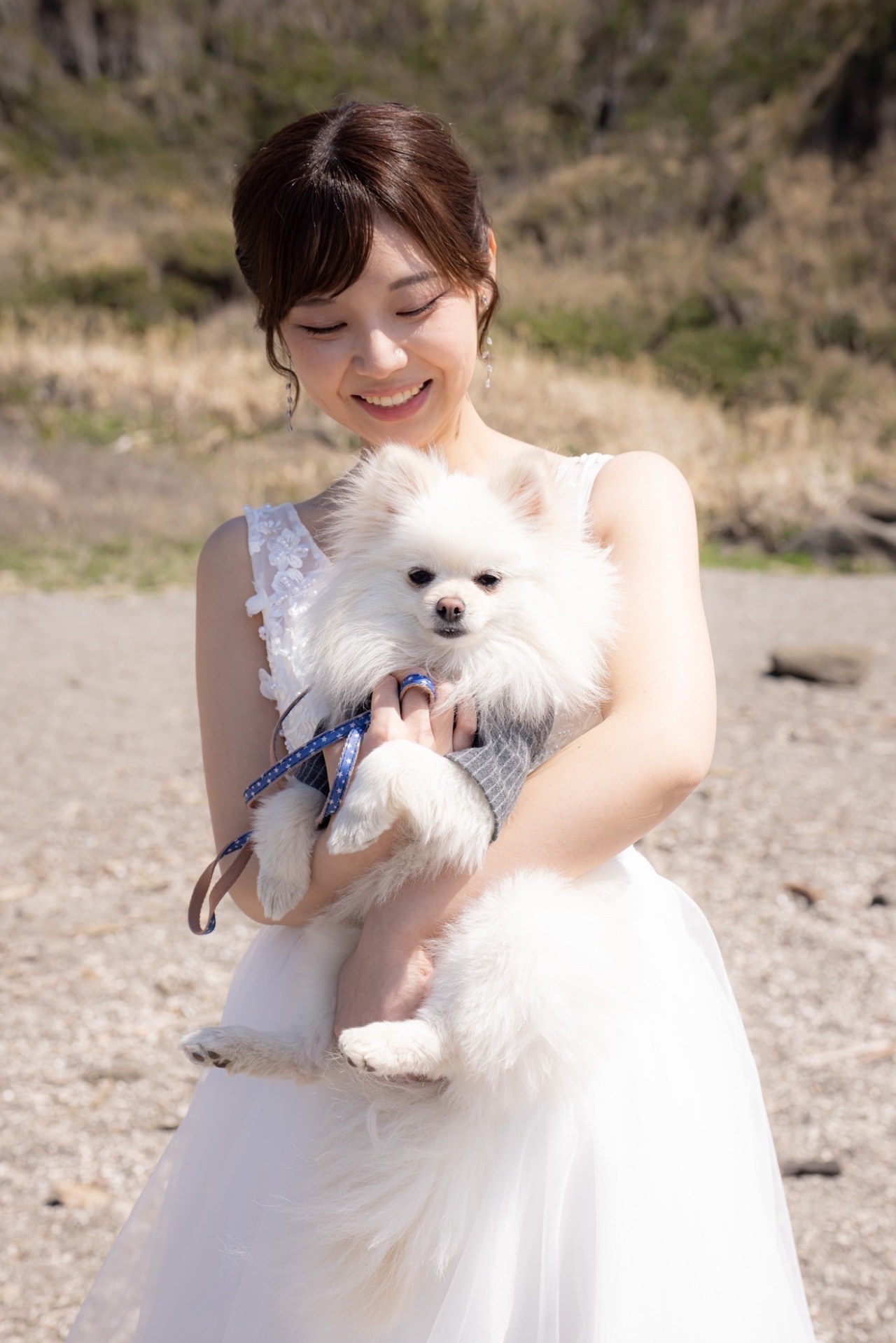 白いウェディングドレス姿で愛犬を抱く新婦