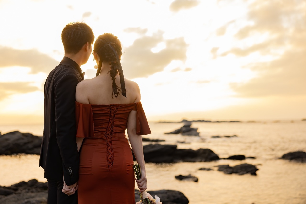 城ヶ島の夕陽と海を眺めながら手をつなぐ新郎新婦の後ろ姿