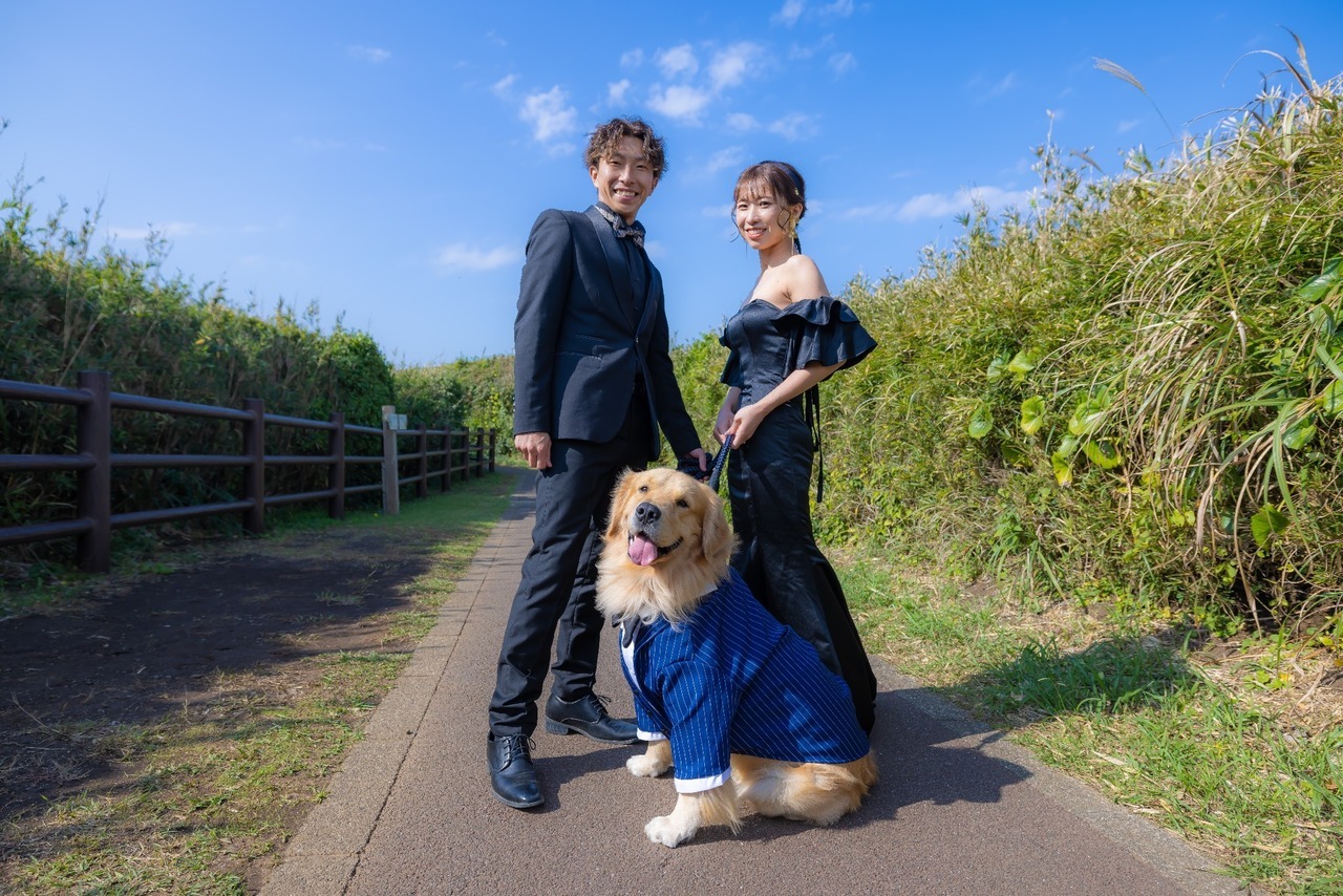 城ヶ島の遊歩道で黒衣装の新郎新婦とスーツ姿の愛犬が並ぶ前撮り写真