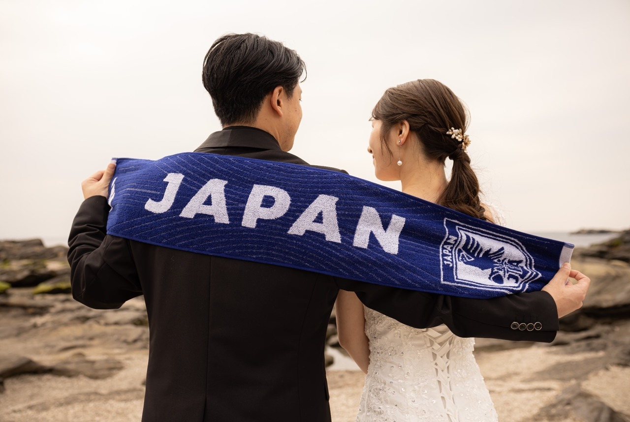 城ヶ島でJAPANのタオルマフラーを広げて撮影する新郎新婦の前撮り
