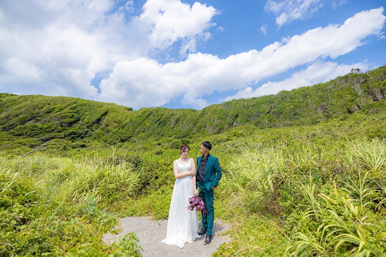 新郎新婦と壮大な城ヶ島の緑あふれる草原と青空